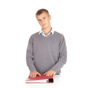 A young man standing with his hands a red binder