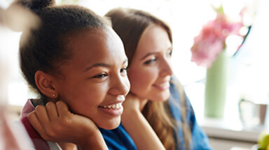 Two young women sitting at a table listening