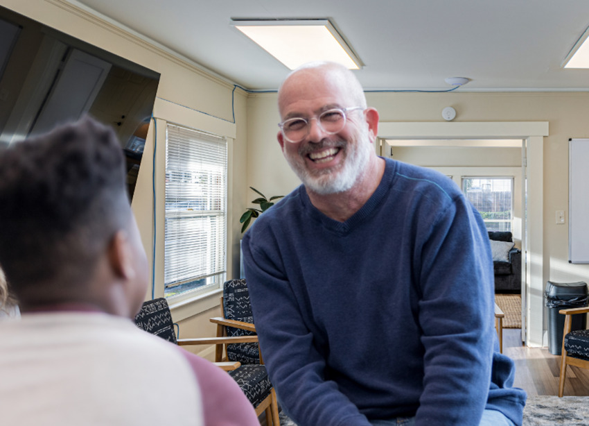 A man smiling while engaing in a conversation