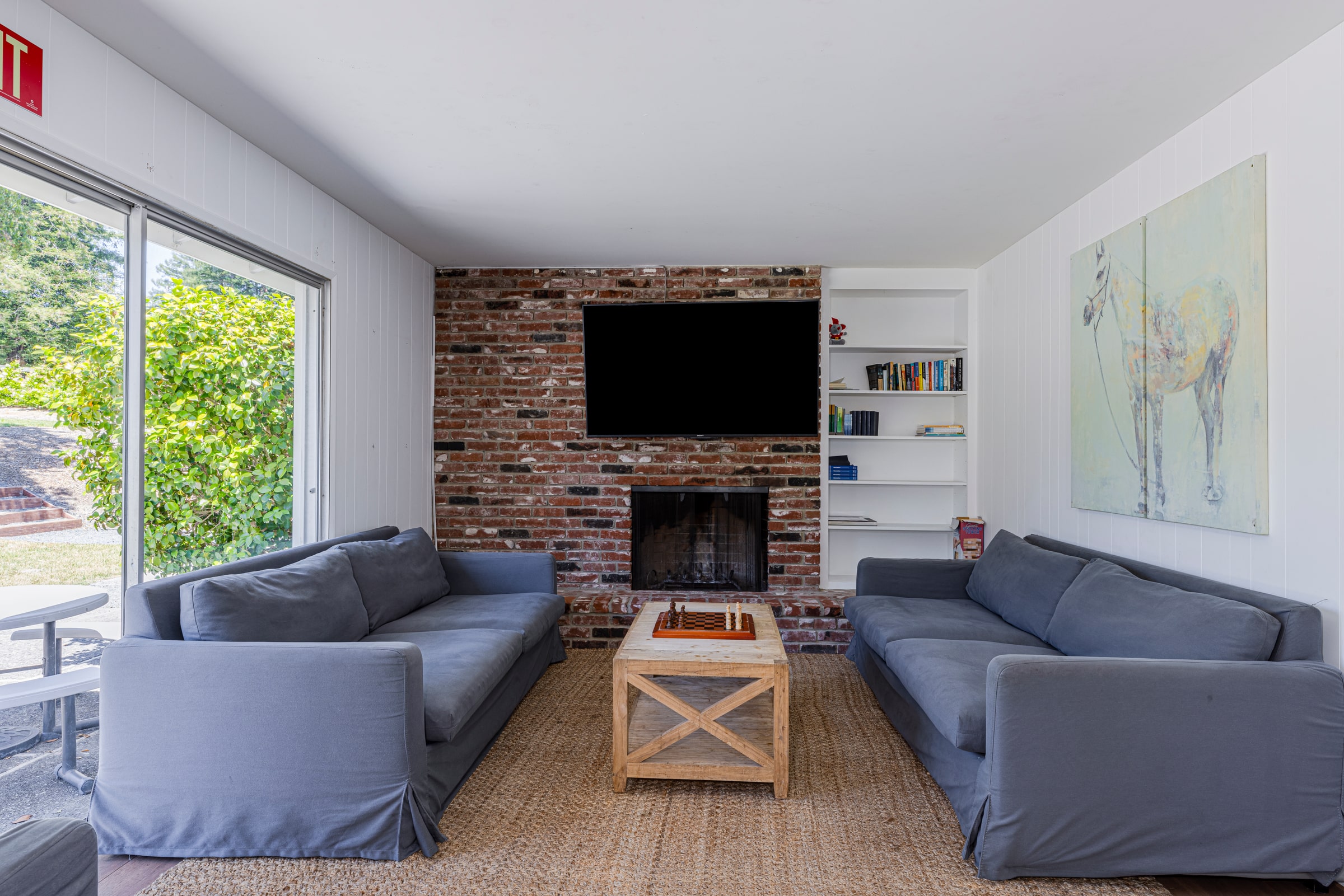 A living room with two blue couches facing each other, a coffee table between them, and a fireplace with a wall-mounted TV.