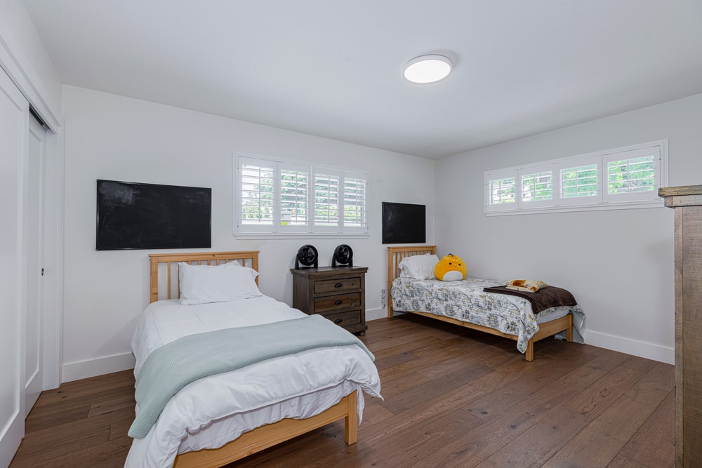 A bedroom with two single beds, a nightstand and dresser.