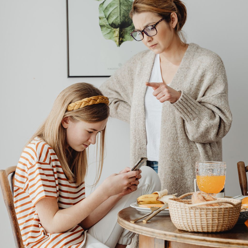 Parent scolding teen girl who is on her phone