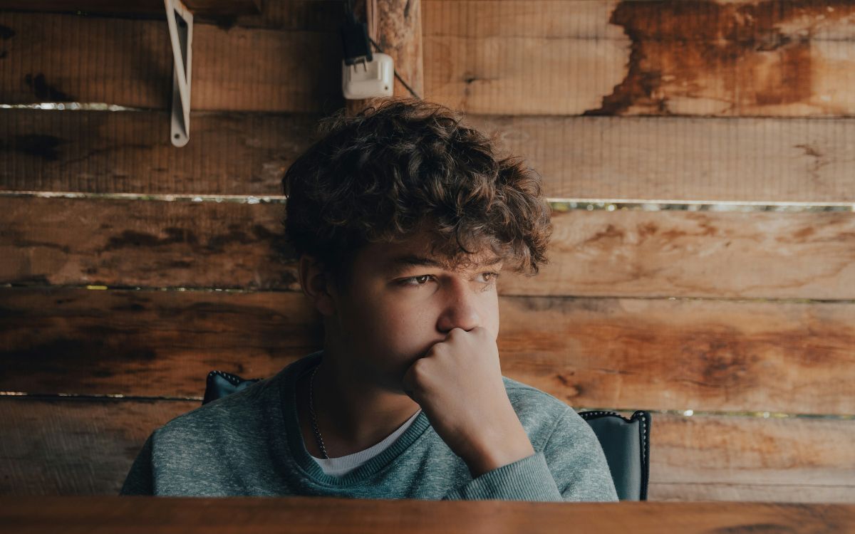 Teen staring off in the distance with their hand on their face