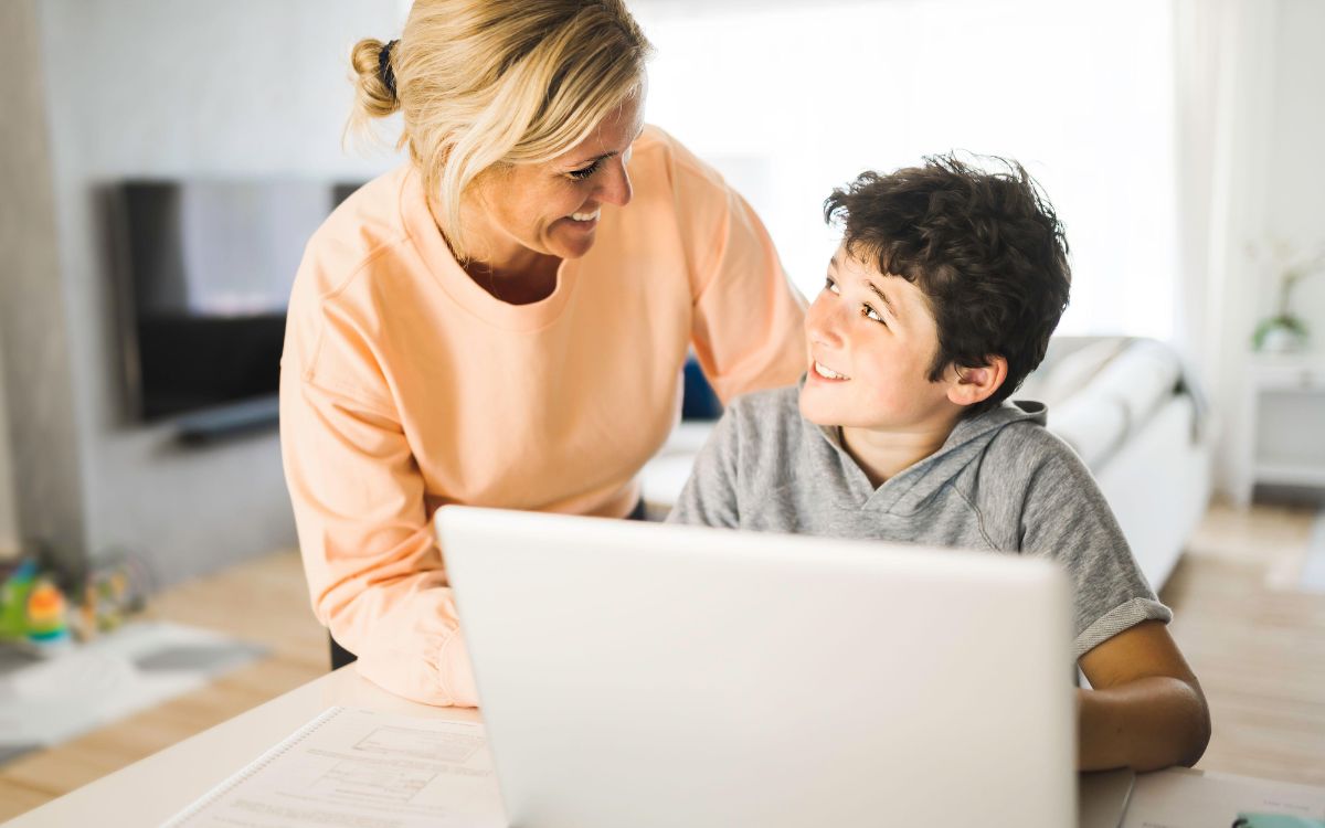 A teen sitting at a computer with their parent helping them