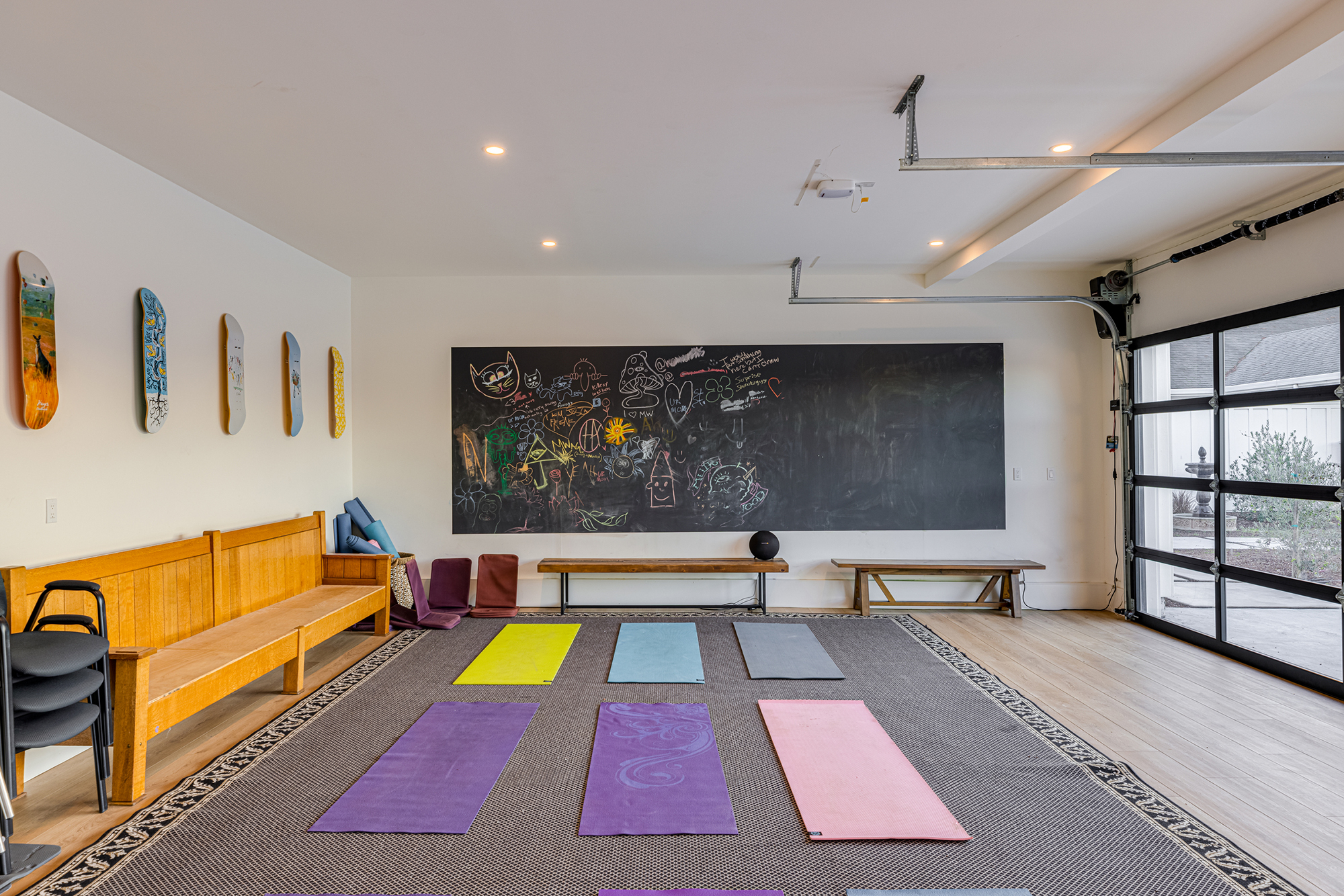 A wellness studio featuring yoga mats, a large chalkboard with drawings, and decorative skateboards on the wall.